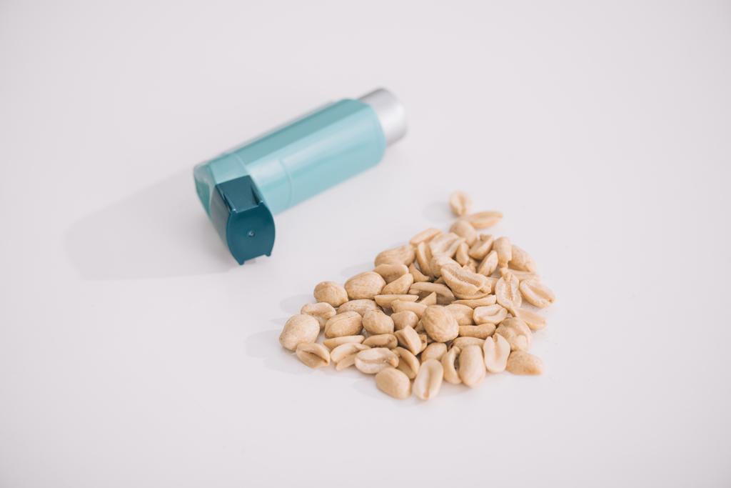 blauer Inhalator in der Nähe schmackhafter nahrhafter Erdnüsse auf grau  - Foto, Bild