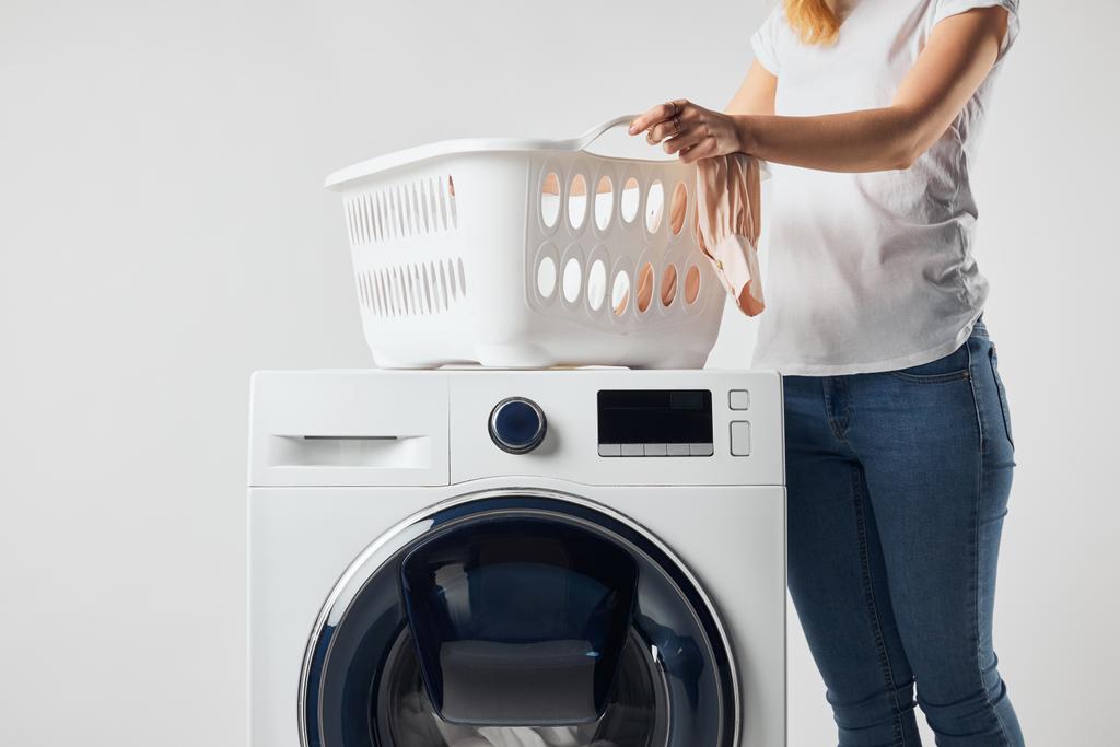 Vue partielle de la femme avec panier landry et machine à laver isolé sur gris
 - Photo, image