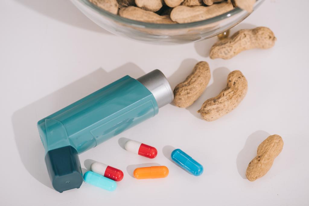 вкусный арахис возле голубого ингалятора и таблетки на сером
  - Фото, изображение