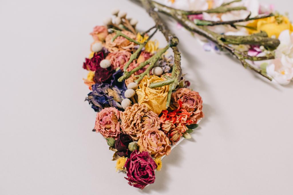 zbliżenie na kompozycji kwiatowych z suszonych i kwitnących kwiatów, w pobliżu gałązki w kształcie płuca na szary  - Zdjęcie, obraz