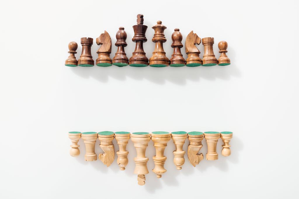 Ansicht der Reihen aus braunen und beigen Schachfiguren aus Holz auf weißem Hintergrund mit Kopierraum - Foto, Bild