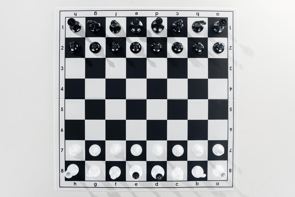 Ansicht des schwarz-weißen Schachbretts mit Schachfiguren auf weißem Hintergrund - Foto, Bild