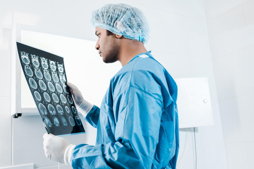 beau médecin en uniforme et coiffe médicale tenant des rayons X dans la clinique
  - Photo, image