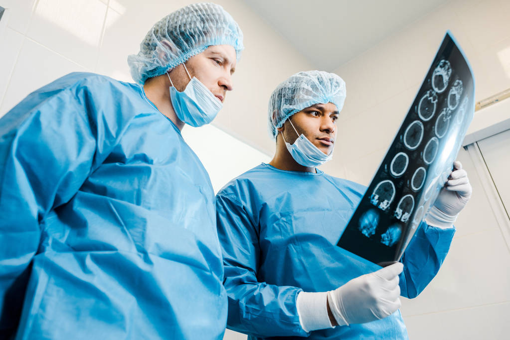 nízký úhel pohledu na pohledné doktory v uniformách a lékařských maskách na rentgenové  - Fotografie, Obrázek