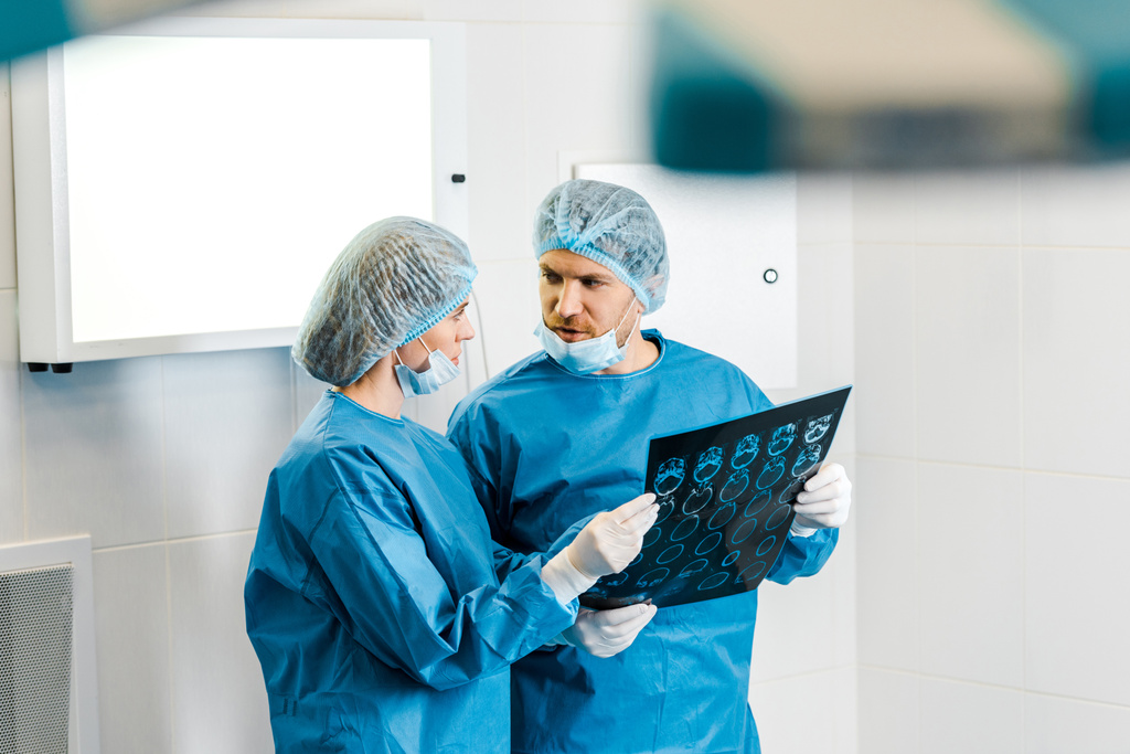 selectieve focus van knappe en mooie artsen in uniformen bedrijf x-ray en praten - Foto, afbeelding