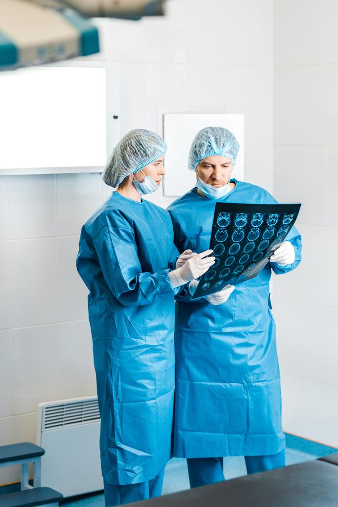 Красивые и красивые врачи в форме проводят рентген и разговаривают в клинике
  - Фото, изображение