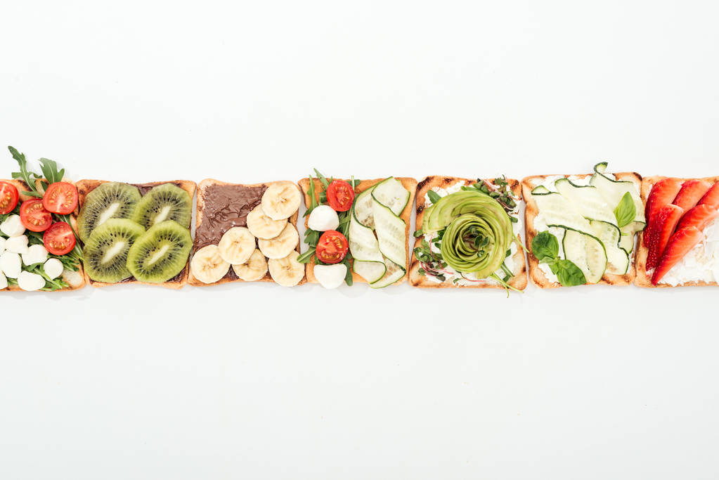 Вид зверху на тости з розрізаними фруктами, овочами та арахісом на білому
 - Фото, зображення