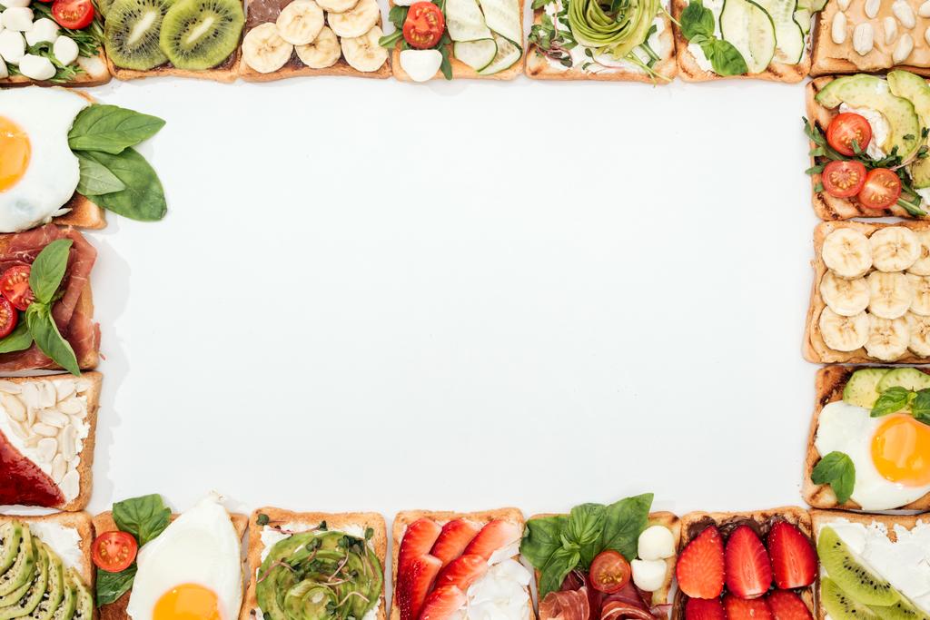 Vista superior de tostadas con frutas, verduras y cacahuetes cortados en blanco
 - Foto, imagen