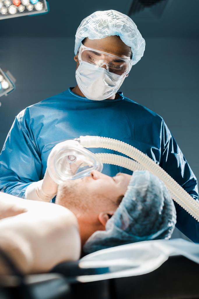 selektywne skupienie się lekarza w mundurze i medyczne Cap wprowadzenie maski na pacjenta  - Zdjęcie, obraz