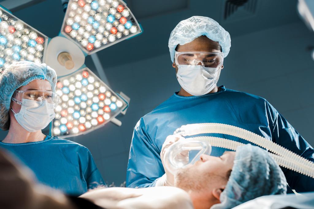 selektywne skupienie się lekarza w mundurze i medyczne Cap wprowadzenie maski na pacjenta  - Zdjęcie, obraz