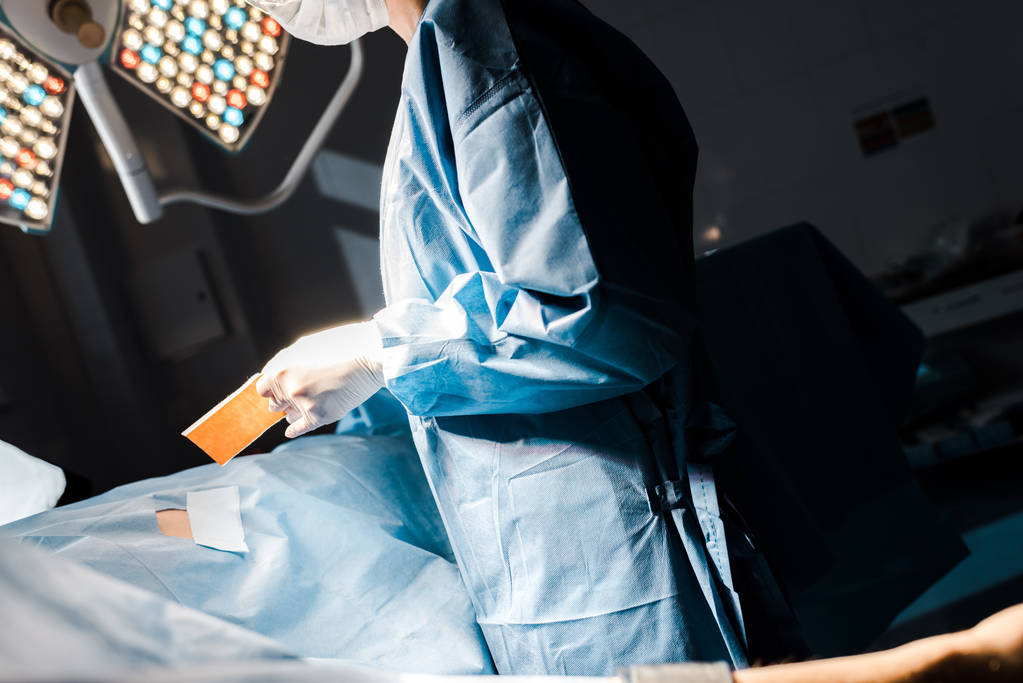 vue recadrée de l'infirmière en uniforme et gants en latex mettant sur bande dans la salle d'opération
 - Photo, image