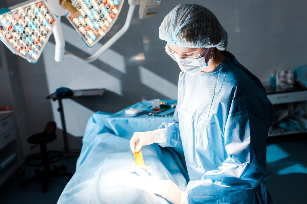 νοσοκόμα με στολή και λάτεξ γάντια βάζοντας σε λωρίδα στο χειρουργείο - Φωτογραφία, εικόνα