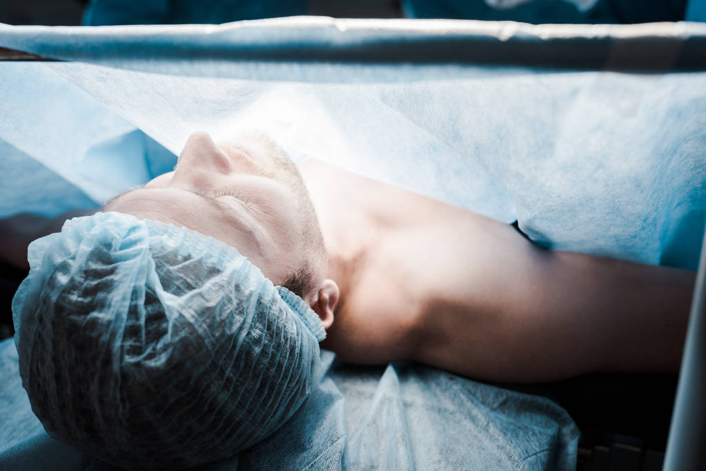 doente adulto com tampa médica deitado na sala de operações
  - Foto, Imagem