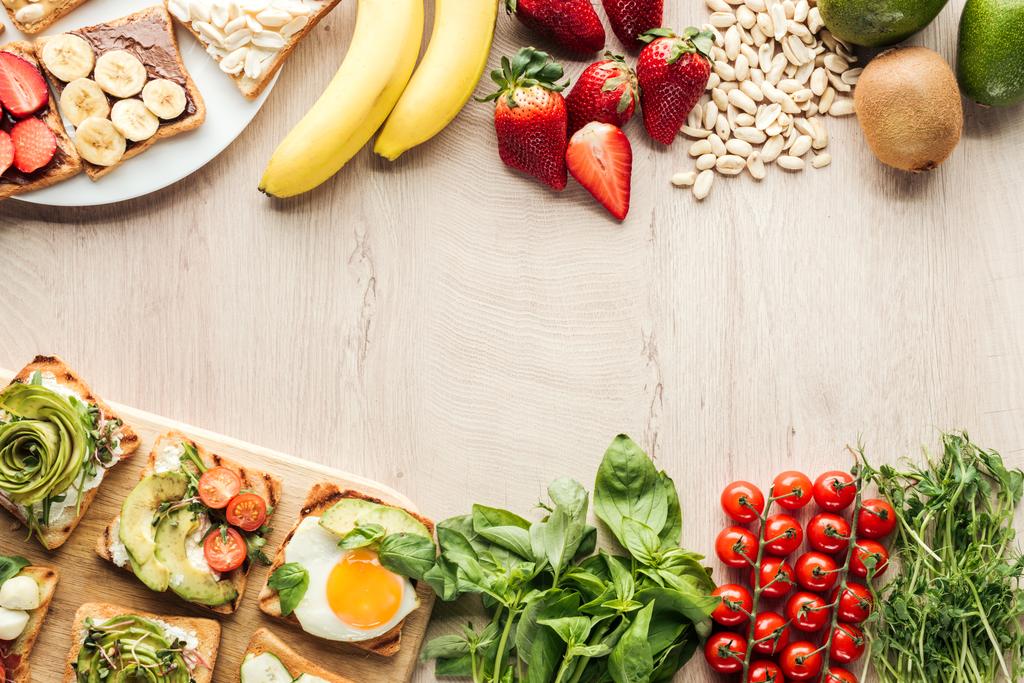 вид зверху інгредієнтів на дерев'яний стіл і тости з овочами на рубаній дошці
 - Фото, зображення