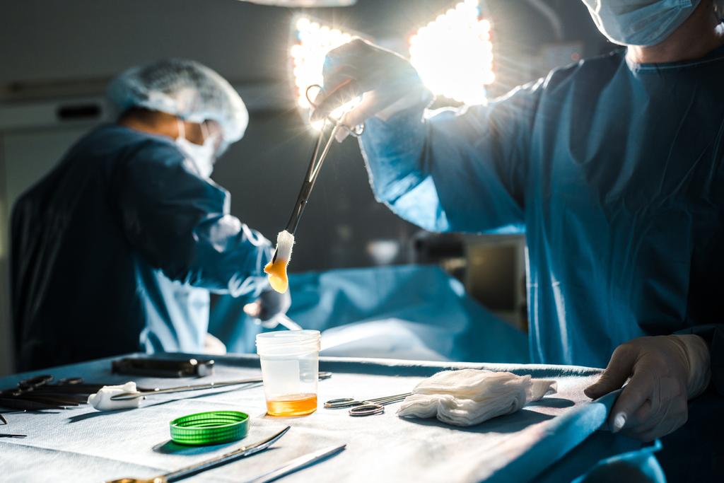 селективний фокус операції хірурга і медсестри, що тримає тампон в операційній кімнаті
  - Фото, зображення