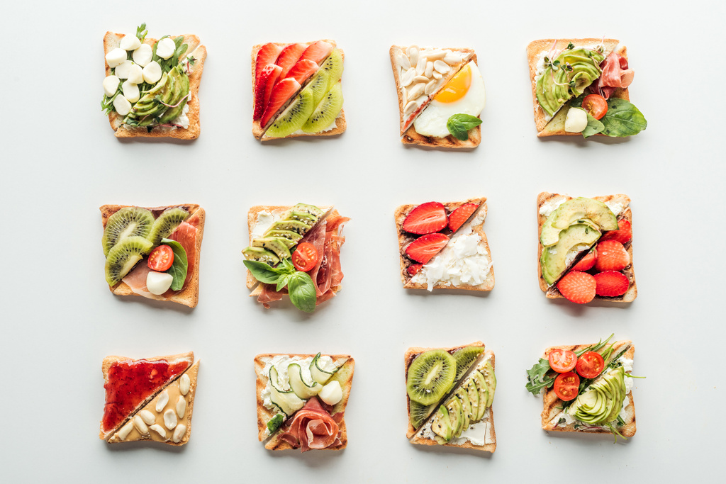 top view of tasty toasts with fruits, vegetables and basil isolated on white - Photo, Image