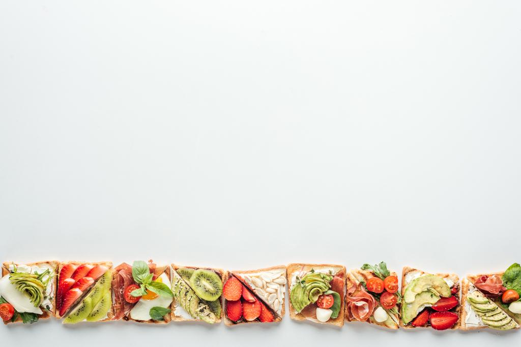 vista dall'alto di fila di pane tostato con frutta e verdura isolata su bianco con spazio copia
 - Foto, immagini