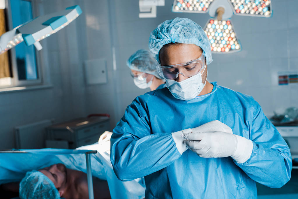 selektywne skupienie się lekarza w jednolitym oddaniem rękawice lateksowe w sali operacyjnej - Zdjęcie, obraz