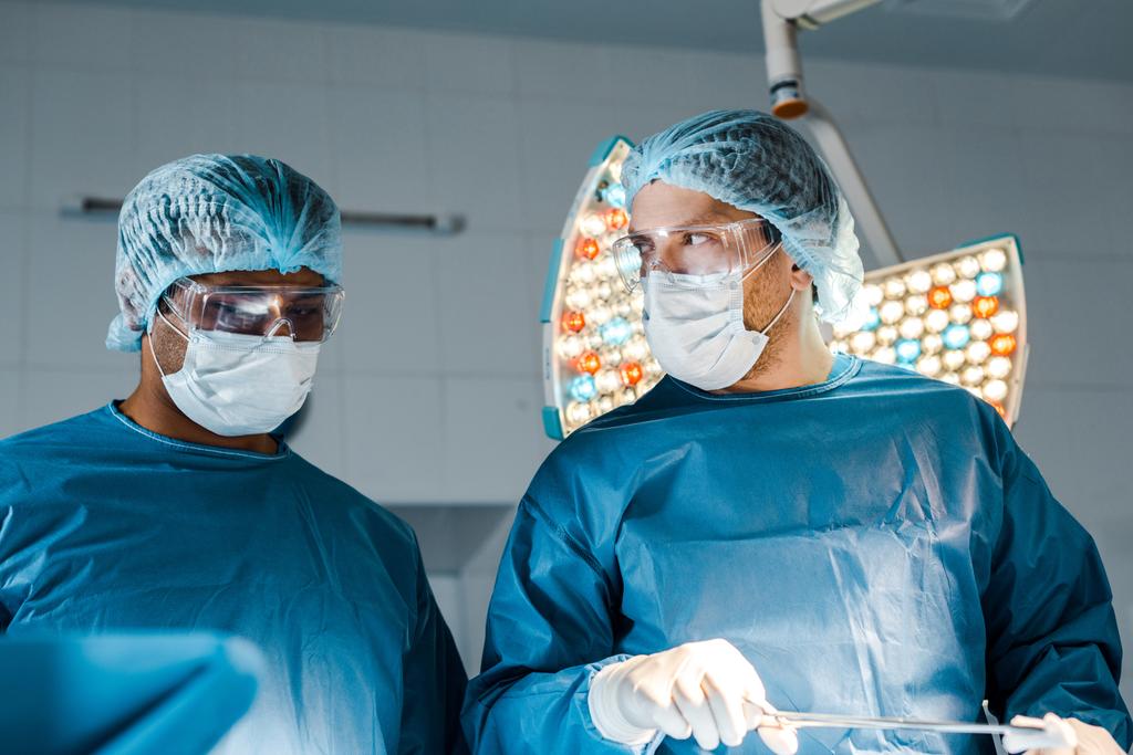 nurse and surgeon in uniforms and medical masks doing operation  - Photo, Image
