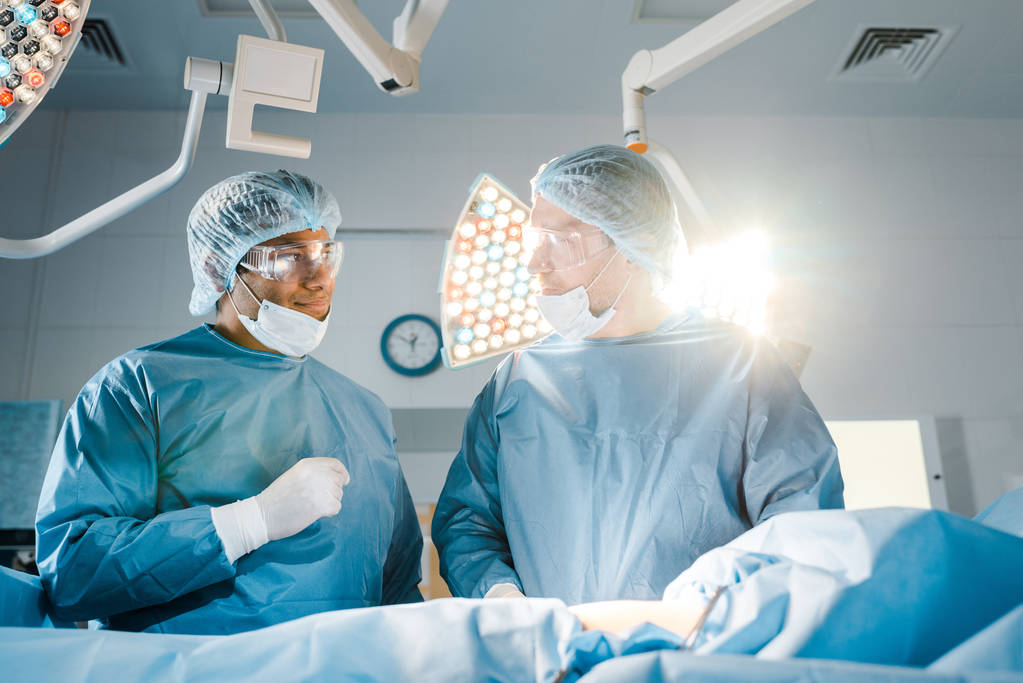nővér és sebész egyenruhát és orvosi maszkok beszél műtőben  - Fotó, kép