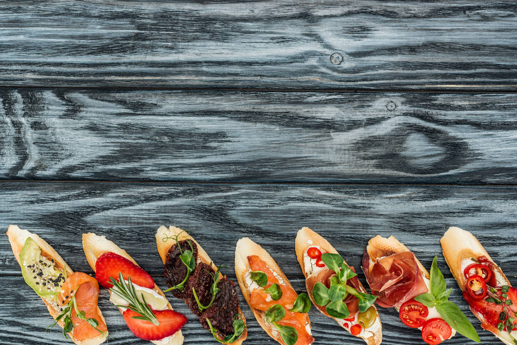 vista superior de la bruschetta italiana con fresas, salmón, hierbas y prosciutto en la mesa de madera
 - Foto, imagen