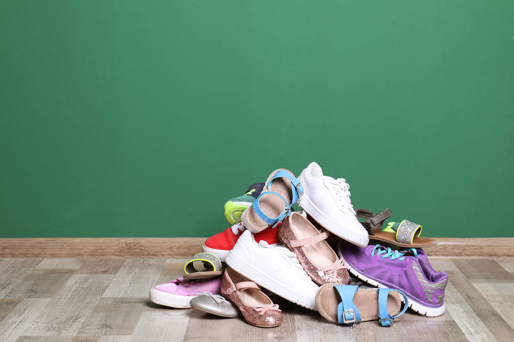 Un mucchio di scarpe diverse sul pavimento contro la parete di colore. Spazio per testo
 - Foto, immagini