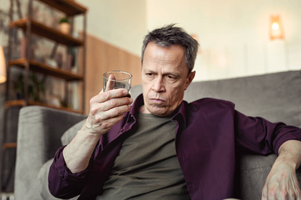 Homme sérieusement déprimé observant l'alcool dans le verre et réfléchissant profondément
 - Photo, image