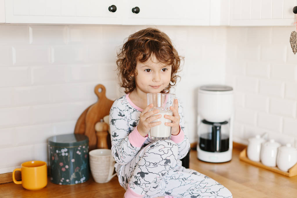 Bambina in pigiama che beve latte
 - Foto, immagini