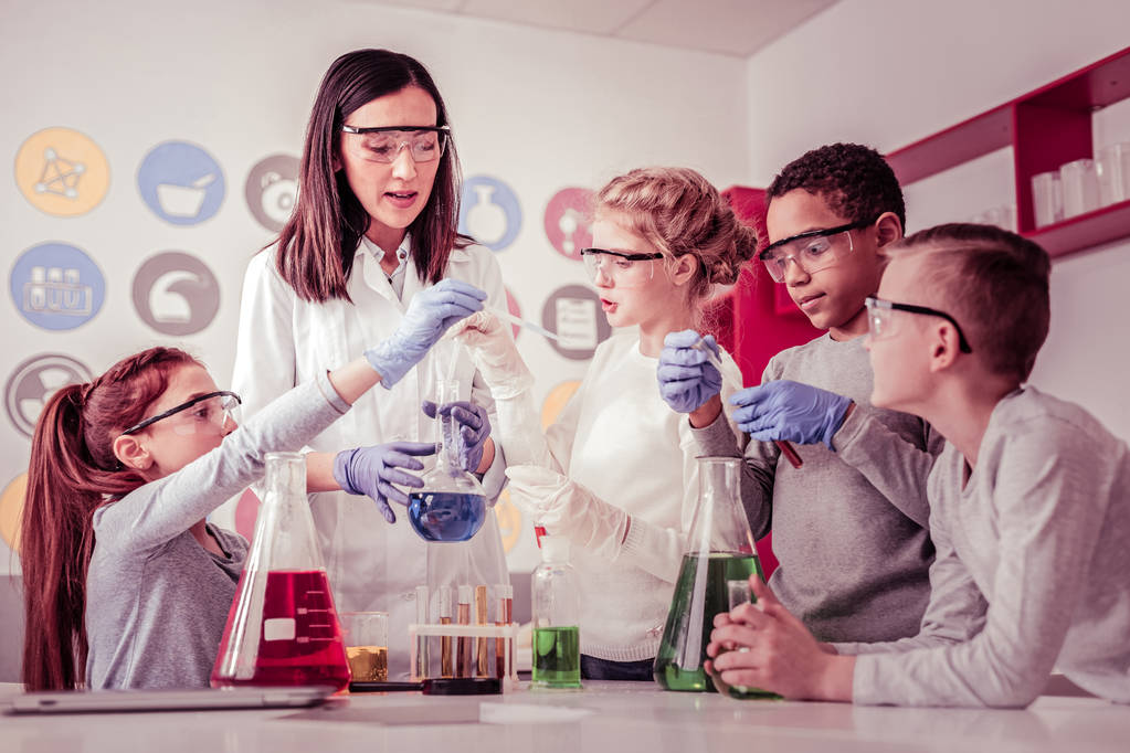 Jóvenes científicos ayudando a su profesor con reactivos
 - Foto, imagen