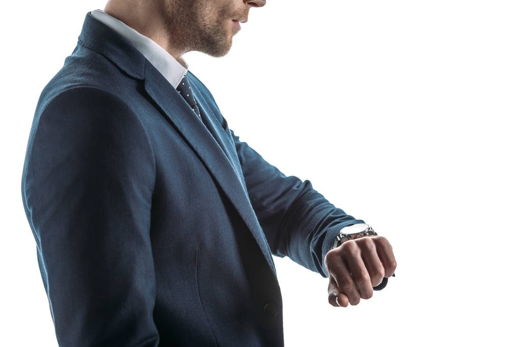 gedeeltelijke weergave van serieuze zakenman kijken naar horloge geïsoleerd op wit - Foto, afbeelding