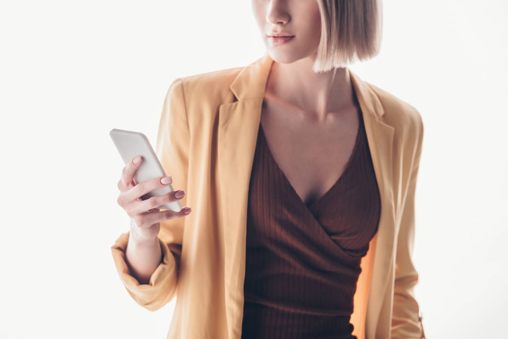 μερική θέα της μόδας γυναίκα κρατώντας smartphone σε γκρι - Φωτογραφία, εικόνα