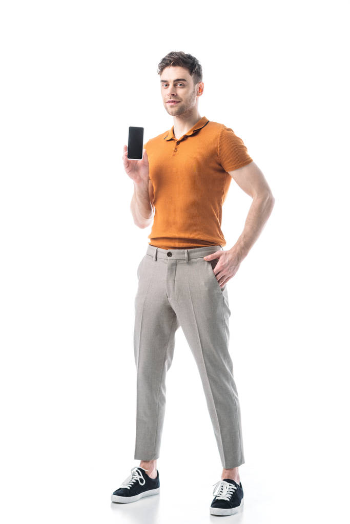dobrze wyglądający człowiek z ręką w kieszeni trzymając smartfon z pustym ekranem na białym tle - Zdjęcie, obraz