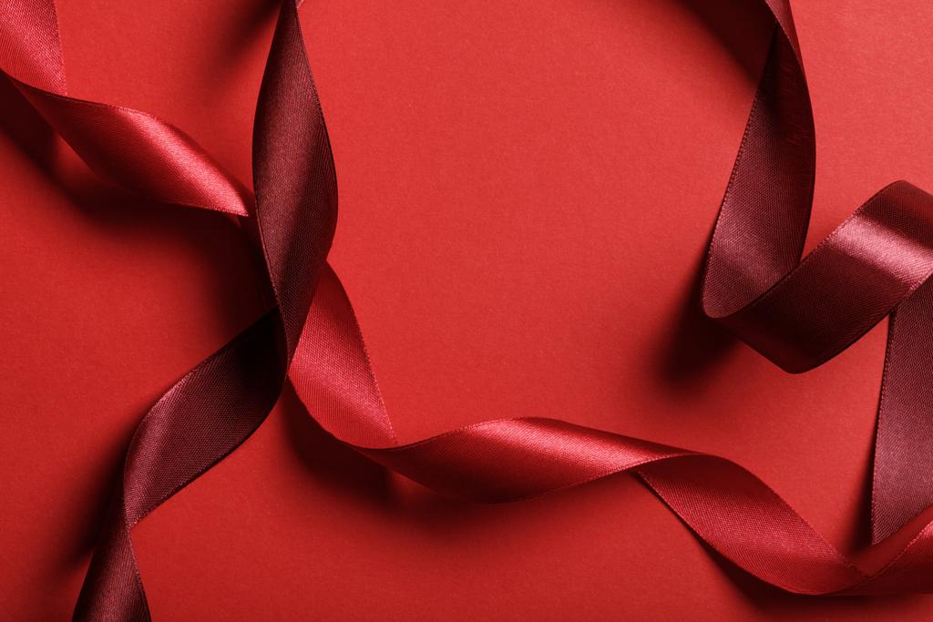 Close up van de gekromde zijden donkerrood en rode linten op rode achtergrond - Foto, afbeelding