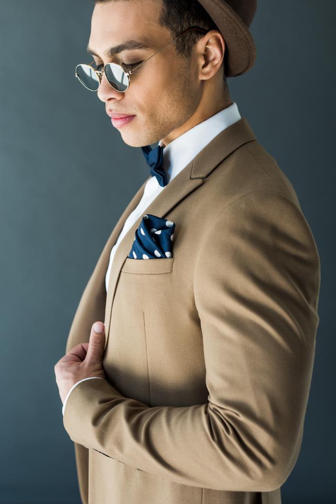 fashionable mixed race man in suit and sunglasses posing isolated on grey - Photo, Image