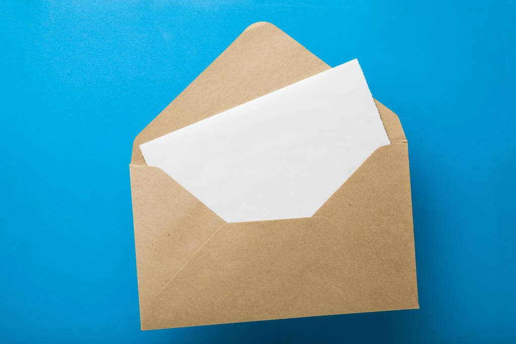 Üres levelet a borítékba, újrahasznosított papír, a kék háttérben - Fotó, kép