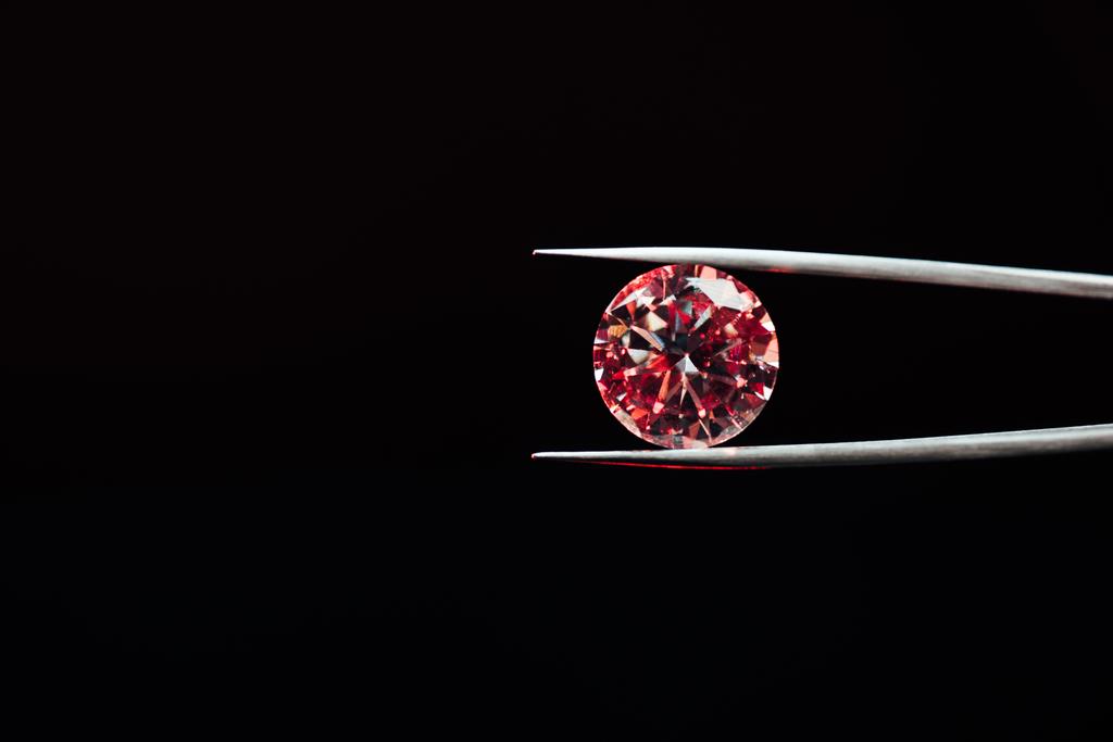 bunte rot funkelnde Diamanten in Pinzette isoliert auf schwarz - Foto, Bild