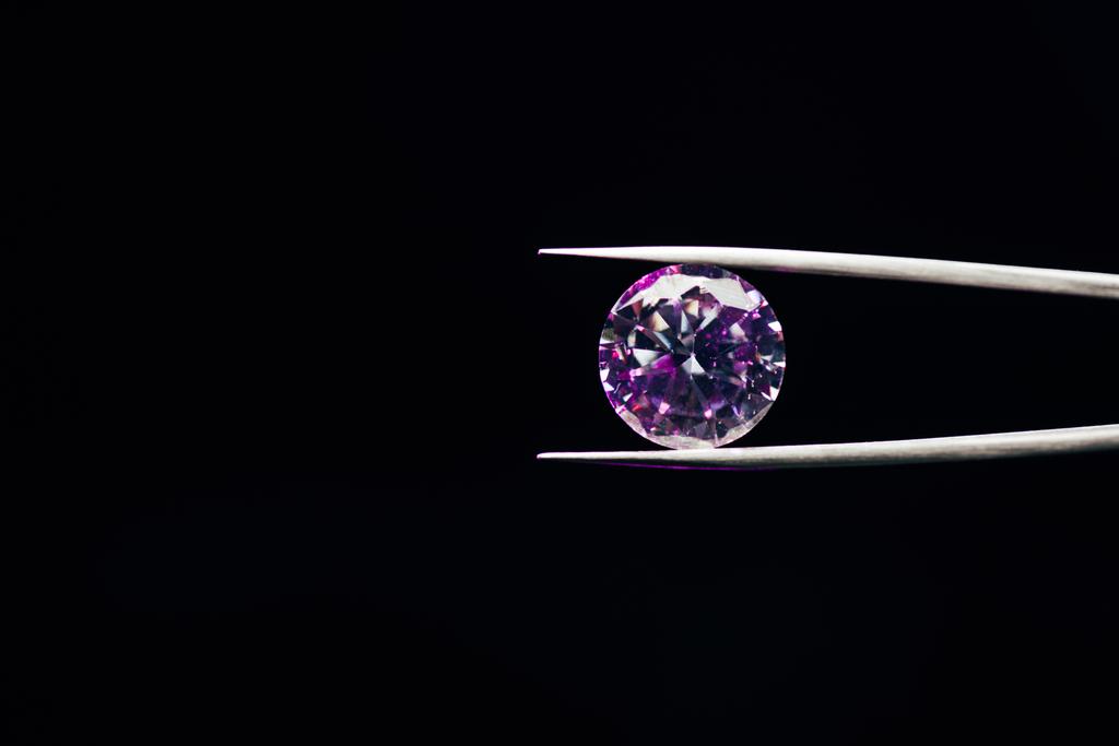 diamante brilhante roxo colorido em pinças isoladas em preto
 - Foto, Imagem