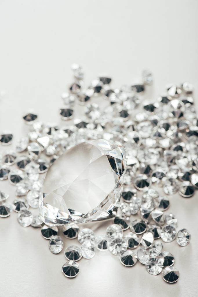 selektiver Fokus von transparentem reinem großen Diamanten unter kleinen auf weißem Hintergrund - Foto, Bild