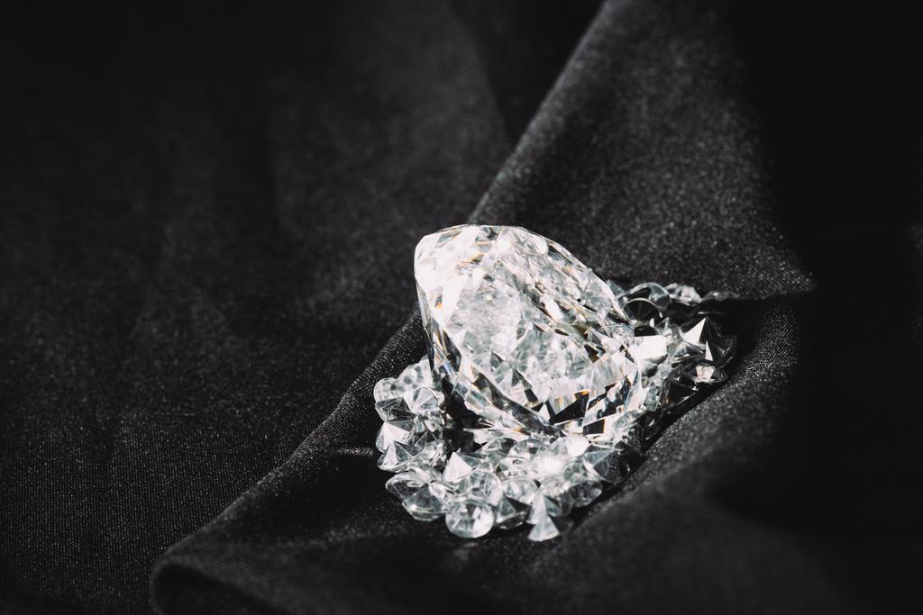 黒い織り目加工の光沢のある布の小さなの中で輝く大きなダイヤモンド  - 写真・画像