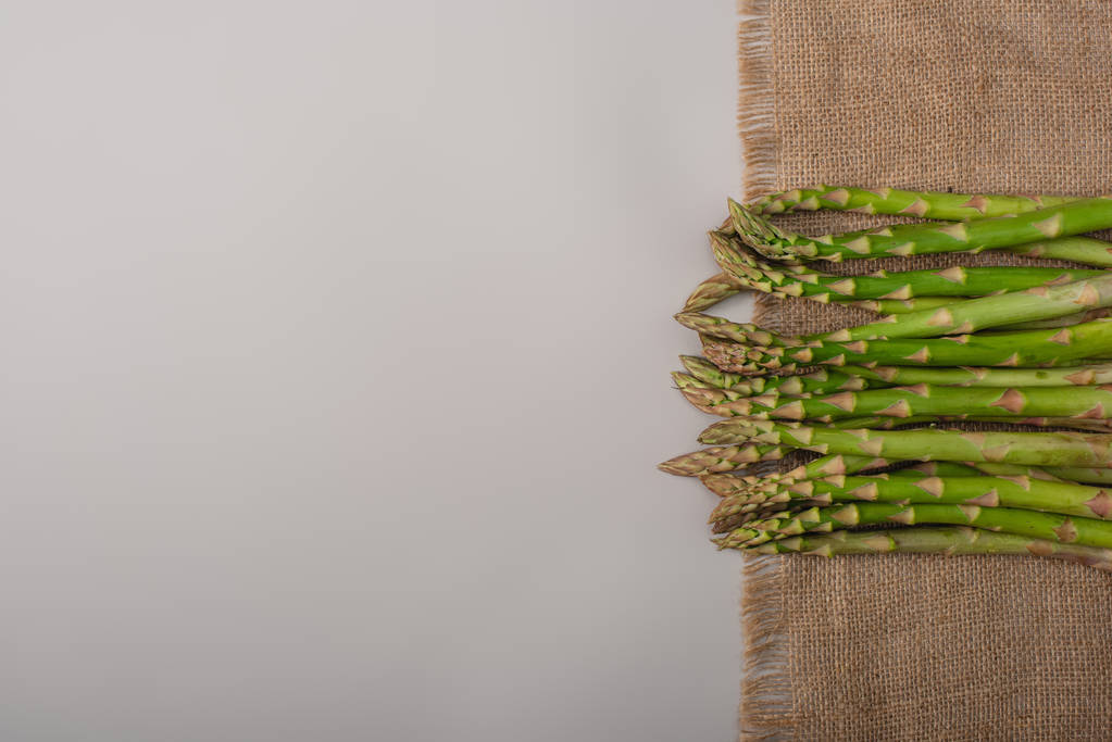vista superior de espargos crus verdes em pano de saco em fundo cinza
 - Foto, Imagem