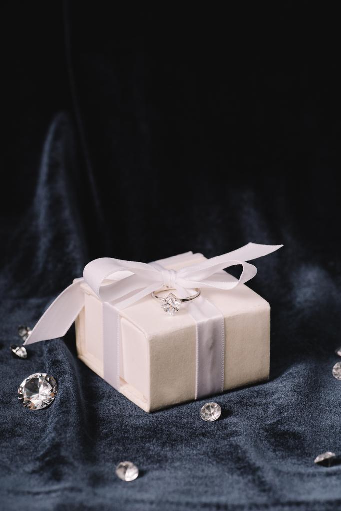bague de fiançailles sur boîte cadeau près de diamants brillants sur tissu bleu
 - Photo, image