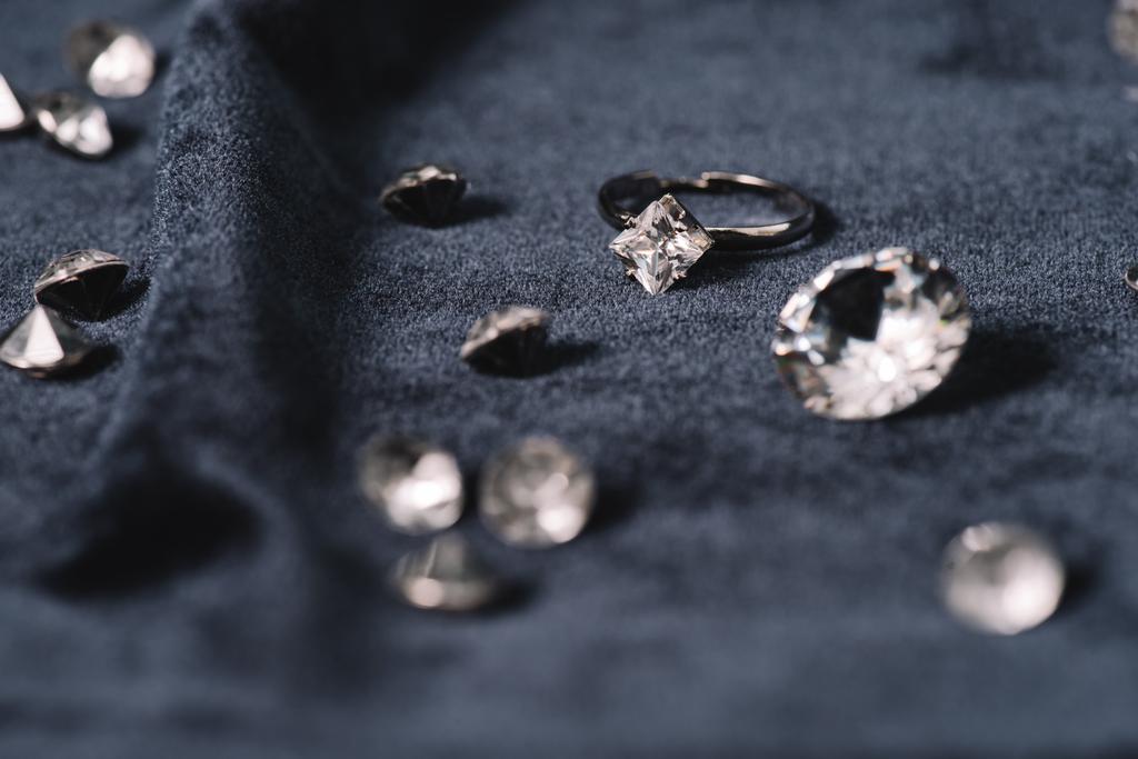 Selektywny fokus pierścionek zaręczynowy w pobliżu błyszczące diamenty na niebieski tkaniny - Zdjęcie, obraz