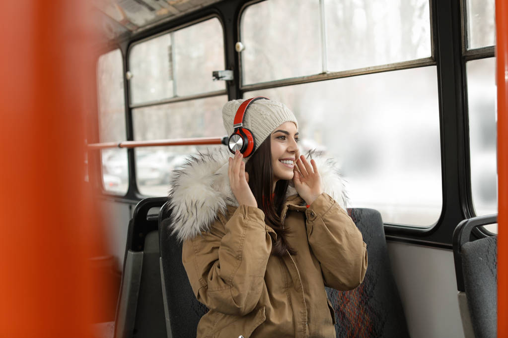 Nuori nainen kuuntelee musiikkia kuulokkeilla julkisessa liikenteessä
 - Valokuva, kuva