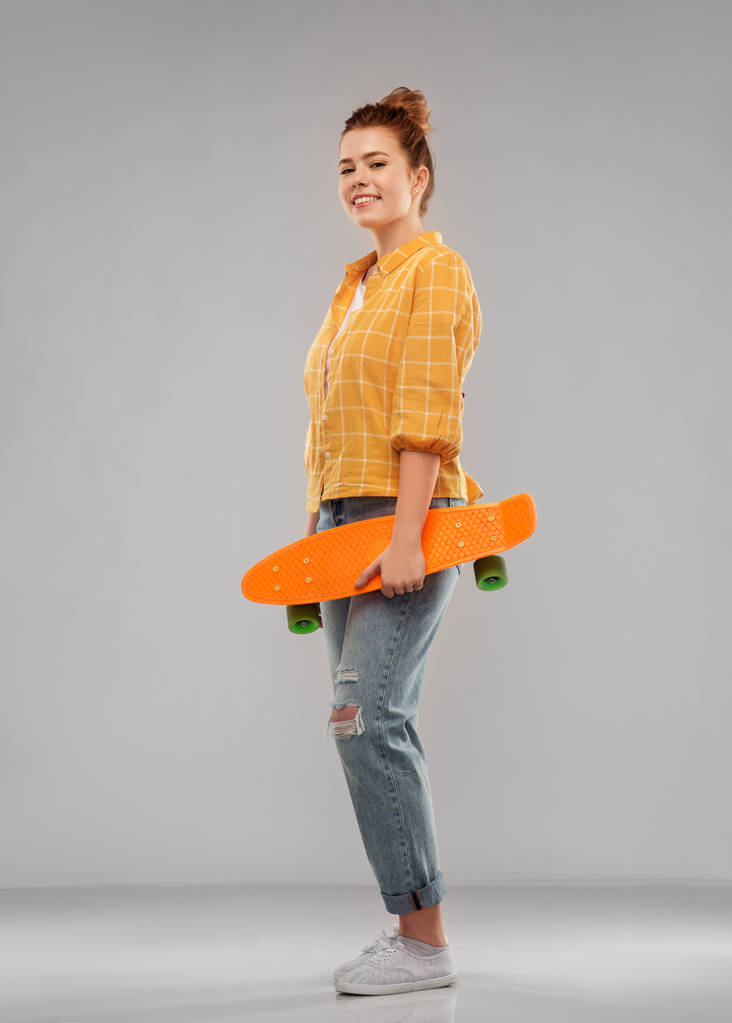 rothaarige Teenagerin mit kurzem Skateboard - Foto, Bild