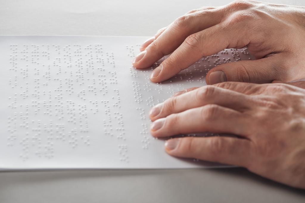 vue recadrée de l'homme lisant du texte en braille avec les mains
  - Photo, image