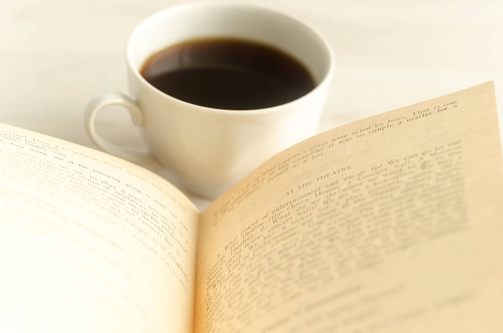 une tasse de café et un livre ouvert sur fond de bois blanc
. - Photo, image