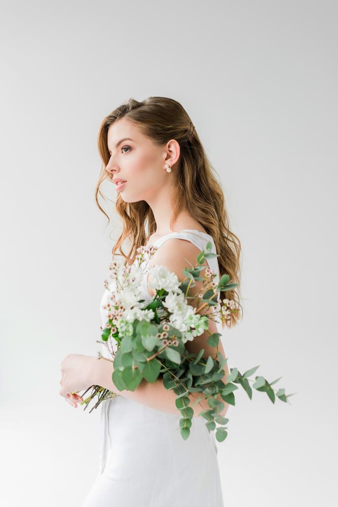 dromerige jonge vrouw in jurk Holding bloemen op wit - Foto, afbeelding