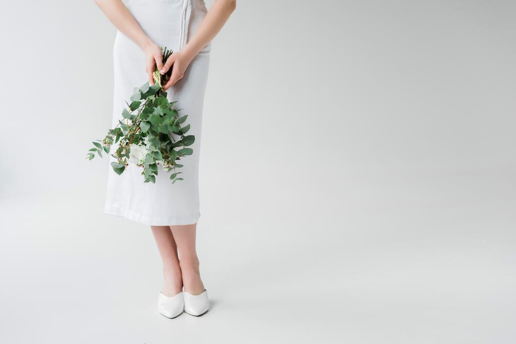 περικομμένη όψη της γυναίκας που στέκεται με λουλούδια σε γκρι - Φωτογραφία, εικόνα