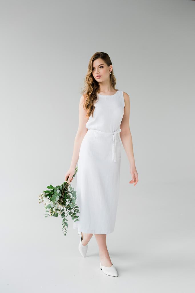приваблива жінка в елегантній сукні, що йде з квітами на сірому
 - Фото, зображення