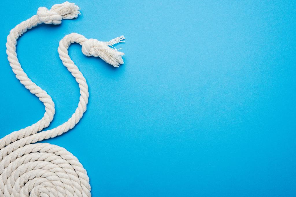white waved and twisted ropes with knots isolated on blue - Photo, Image